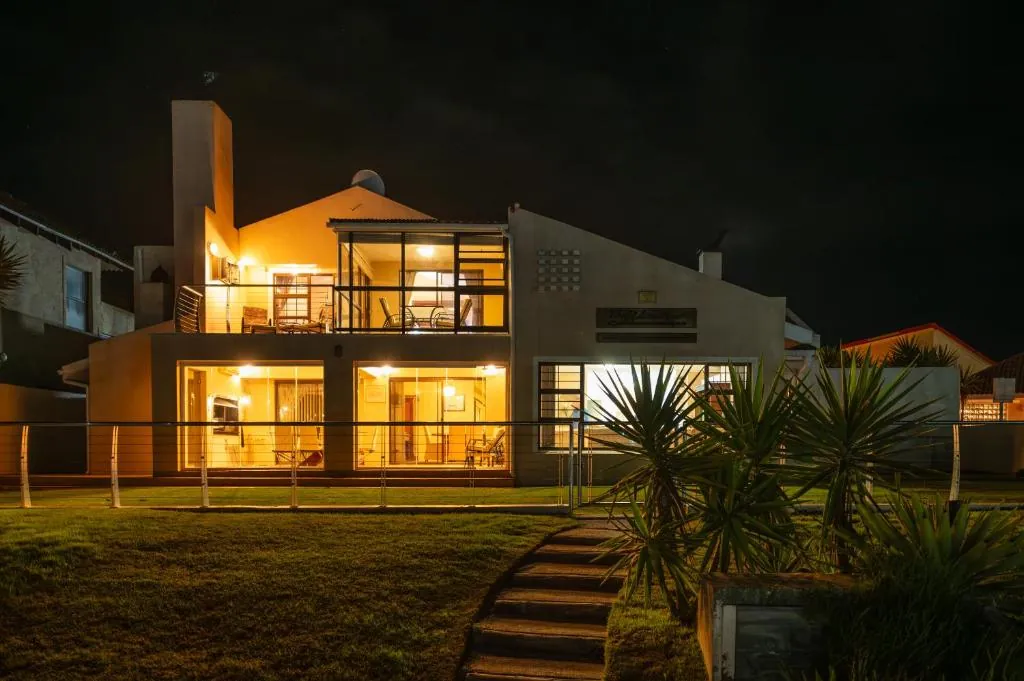 The villa lit up at night, seen from the marina lawn